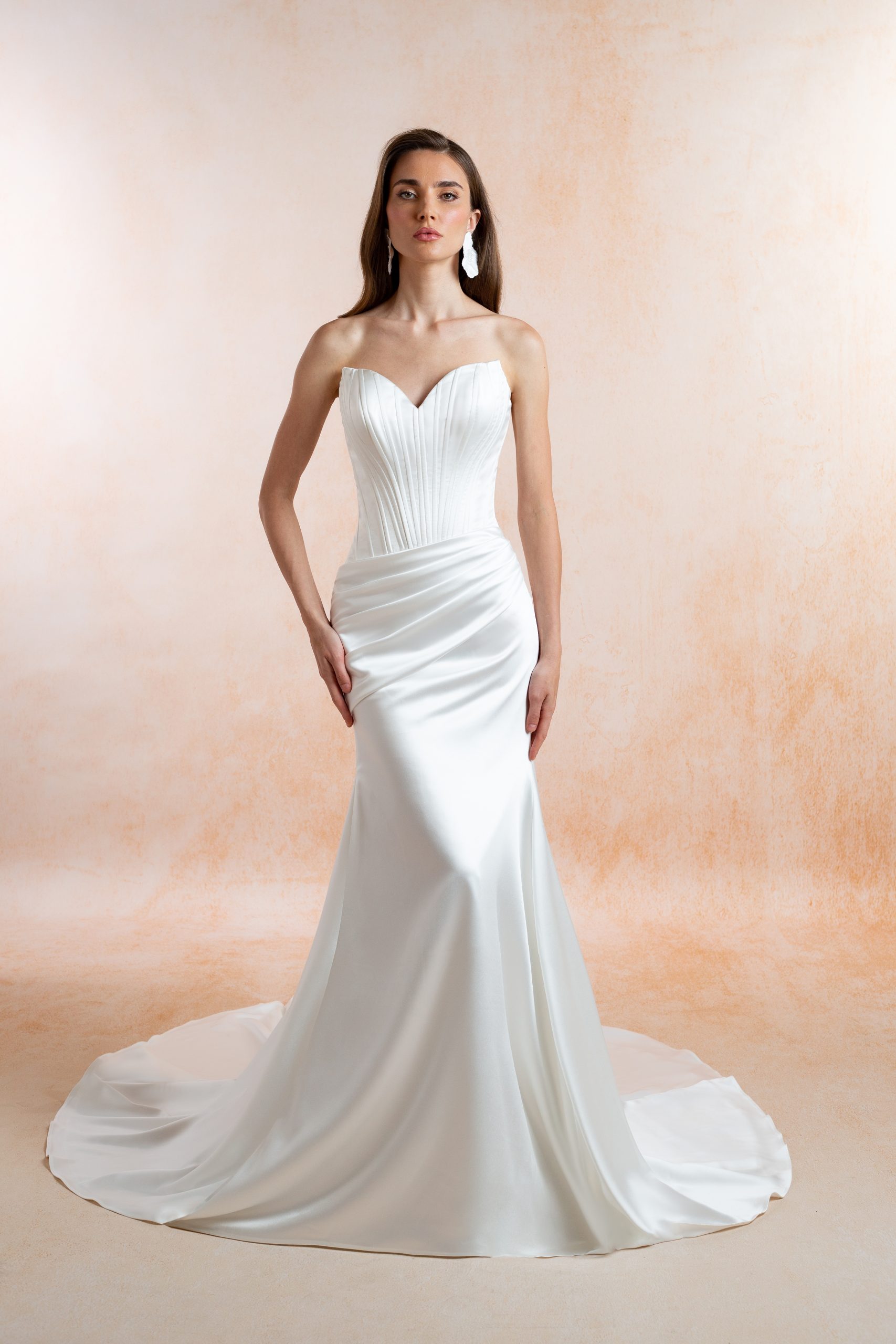 Model wearing the Iris strapless satin wedding dress with a sweetheart neckline, pleated corset bodice, draped hips and flared skirt with a train.