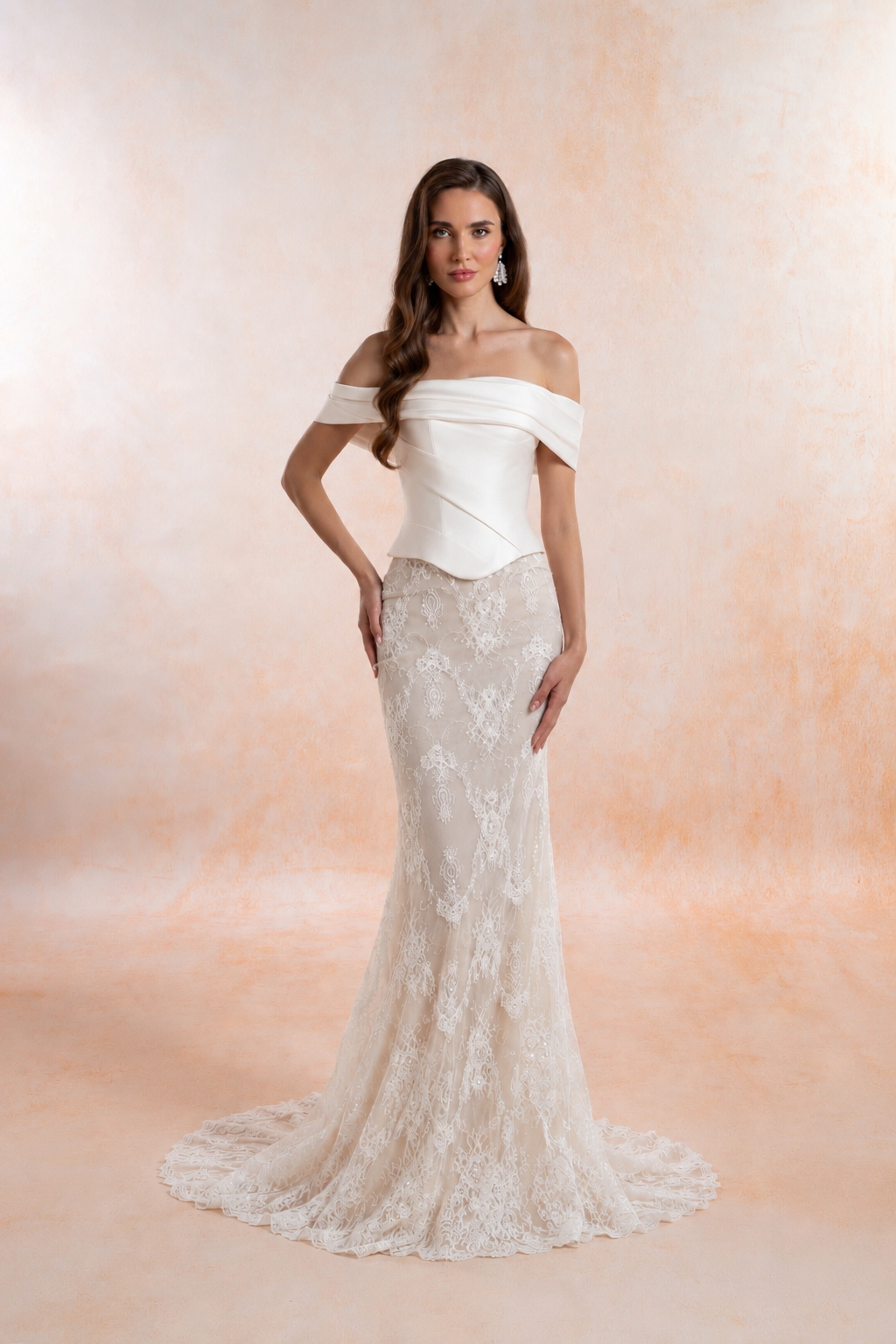 Model wearing a two-piece fit-and-flare wedding dress with a beaded lace gown and off-the-shoulder Mikado corset featuring a straight neckline, pointed waist and lace-up back.